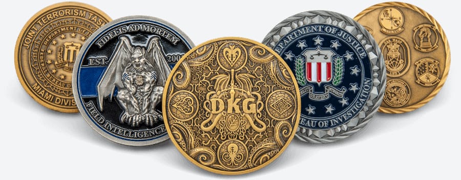 A range of intricately designed challenge coins including one from the Joint Terrorism Task Force, one with a motto 'FIDELITY, BRAVERY, INTEGRITY' and a gargoyle figure, a decorative 'DKG' HP Lovecraft coin, and a Department of Justice FBI emblem. The coins exhibit a variety of metallic finishes and detailed embossing.