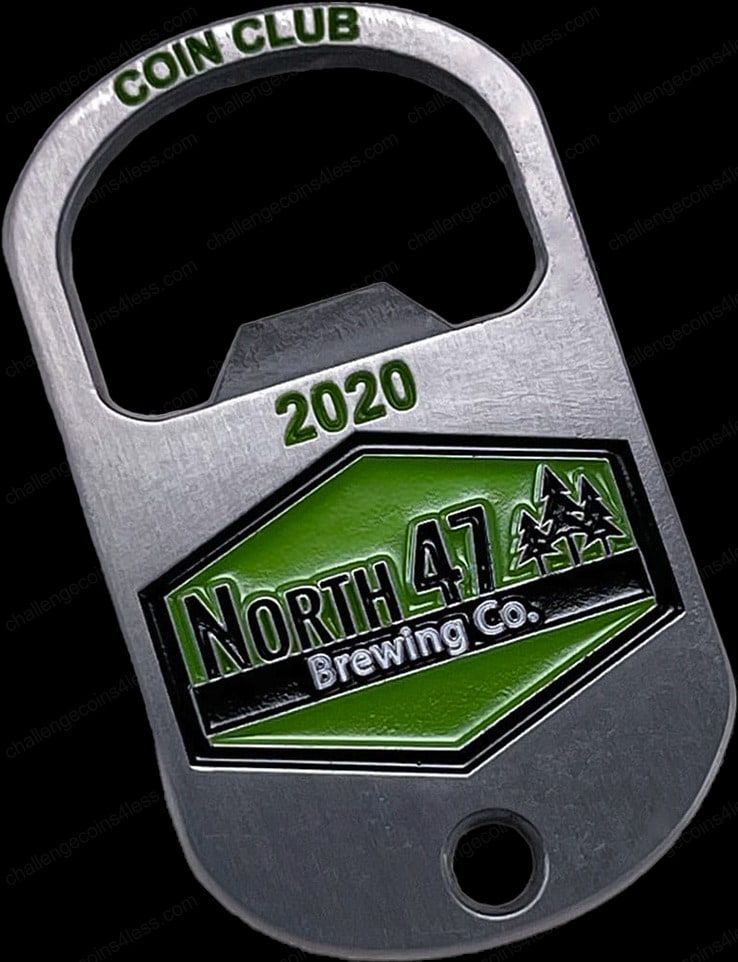 A custom dog tag-shaped coin with a built-in bottle opener, engraved with 'COIN CLUB 2020' at the top. It features the logo of 'North 47 Brewing Co.' with a mountain and pine tree silhouette against a dark green backdrop, highlighting the brand’s adventurous spirit.
