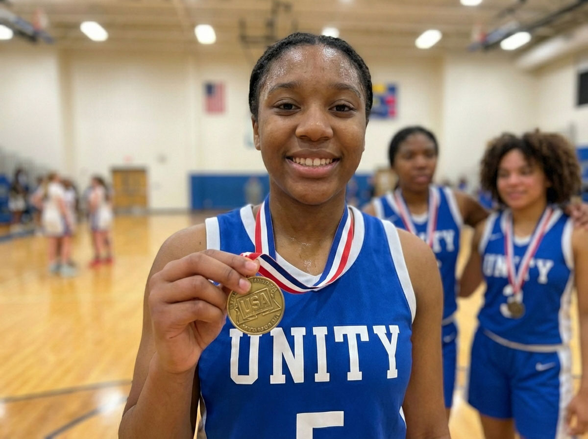 Unity basketball player smiling and proudly holding up a gold medal on the court after winning a tournament.